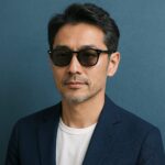 青基調の背景でサングラスをかけた清潔感のある40〜50代日本人男性の半リアルイラスト。都会的で上品な印象。