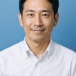 青基調の背景で微笑む清潔感のある40〜50代日本人男性（半リアル）
