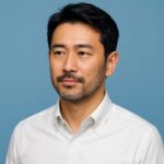 青い背景で清潔感のある40〜50代日本人男性の半リアルポートレート（婚活向け髭スタイルイメージ）