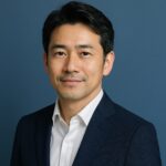 清潔感のある40〜50代日本人男性が青い背景で微笑む半リアルなポートレート写真