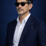 清潔感のある40〜50代日本人男性が、整えた髪とヒゲで落ち着いた表情を見せている青基調の人物写真