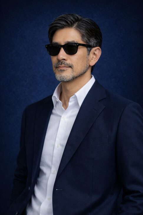 清潔感のある40〜50代日本人男性が、整えた髪とヒゲで落ち着いた表情を見せている青基調の人物写真