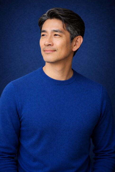 清潔感のある40代〜50代日本人男性のポートレート 深いブルー背景の半リアルアイキャッチ画像